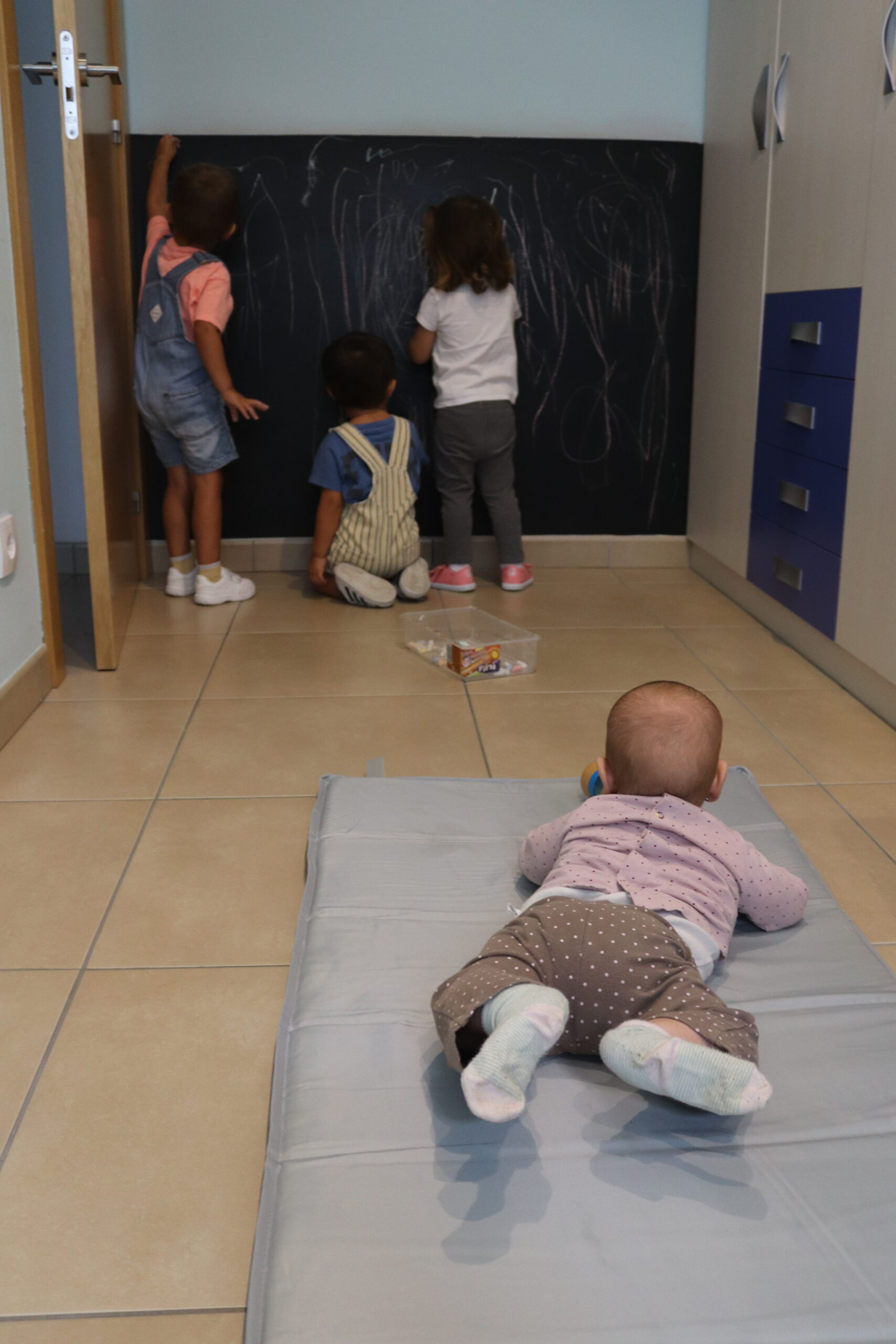 Niños pintando con tiza en una pared preparada de la Casa Amiga 